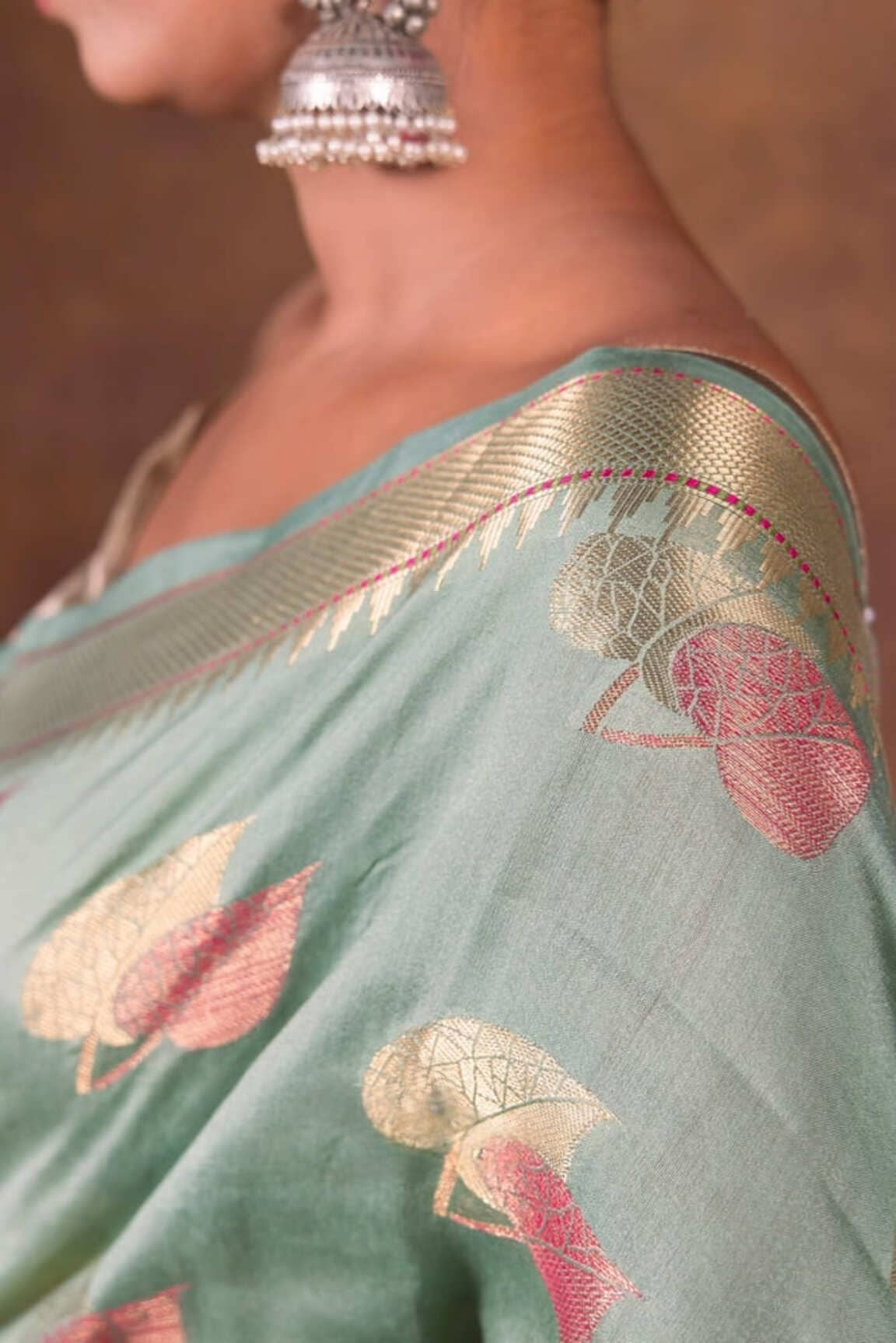 Mint green saree pallu close-up with gold border and multicolor floral patterns