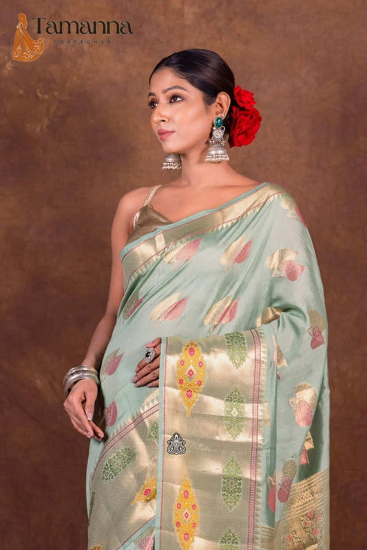 Mint green saree drape with gold border, scattered leaf prints, and multicolor accents