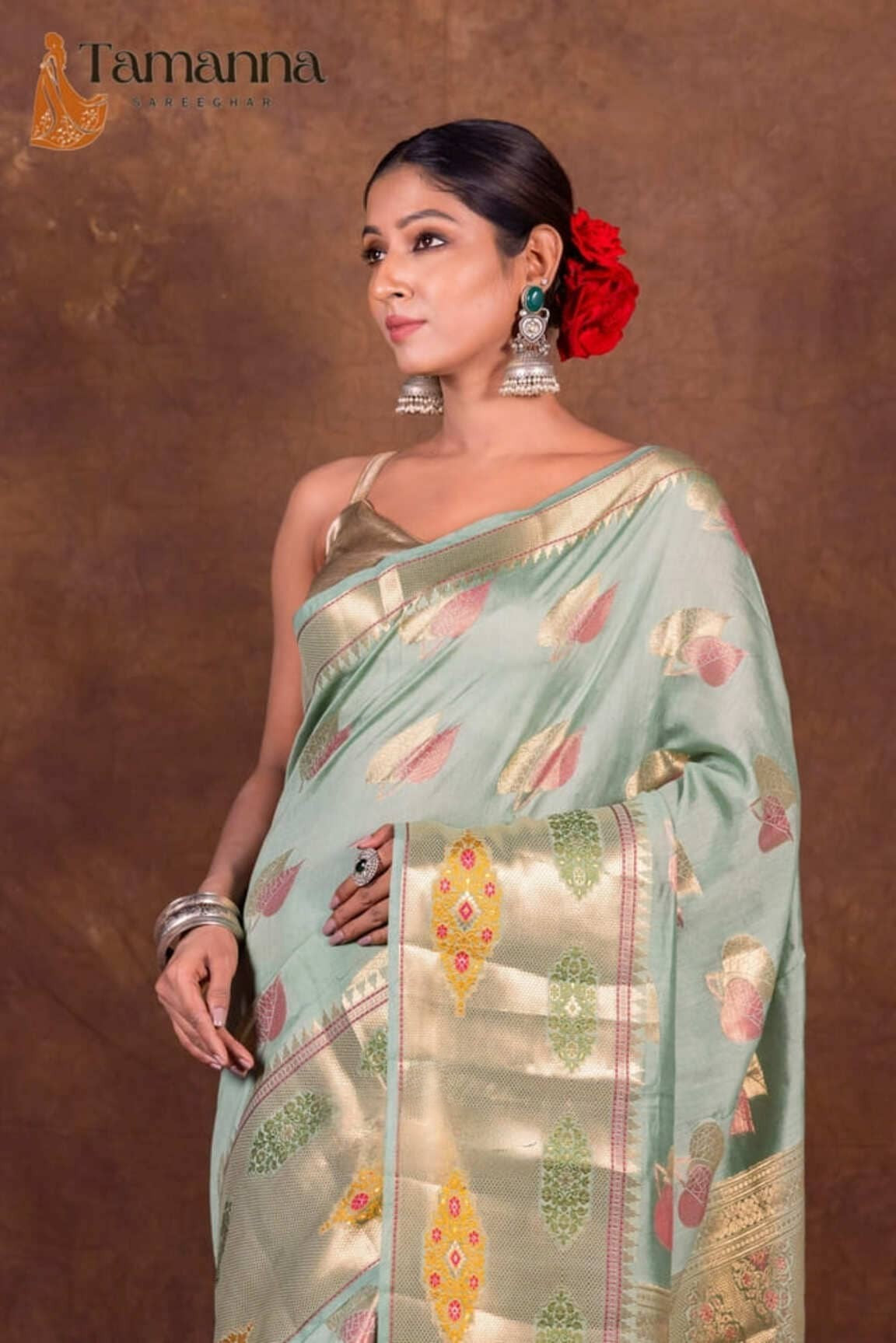 Mint green Banarasi saree draped on model with gold border and colorful motifs