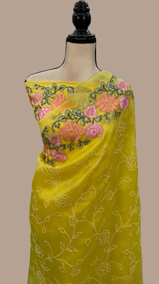 Mustard yellow organza saree featuring pink floral panel and allover chikankari motifs