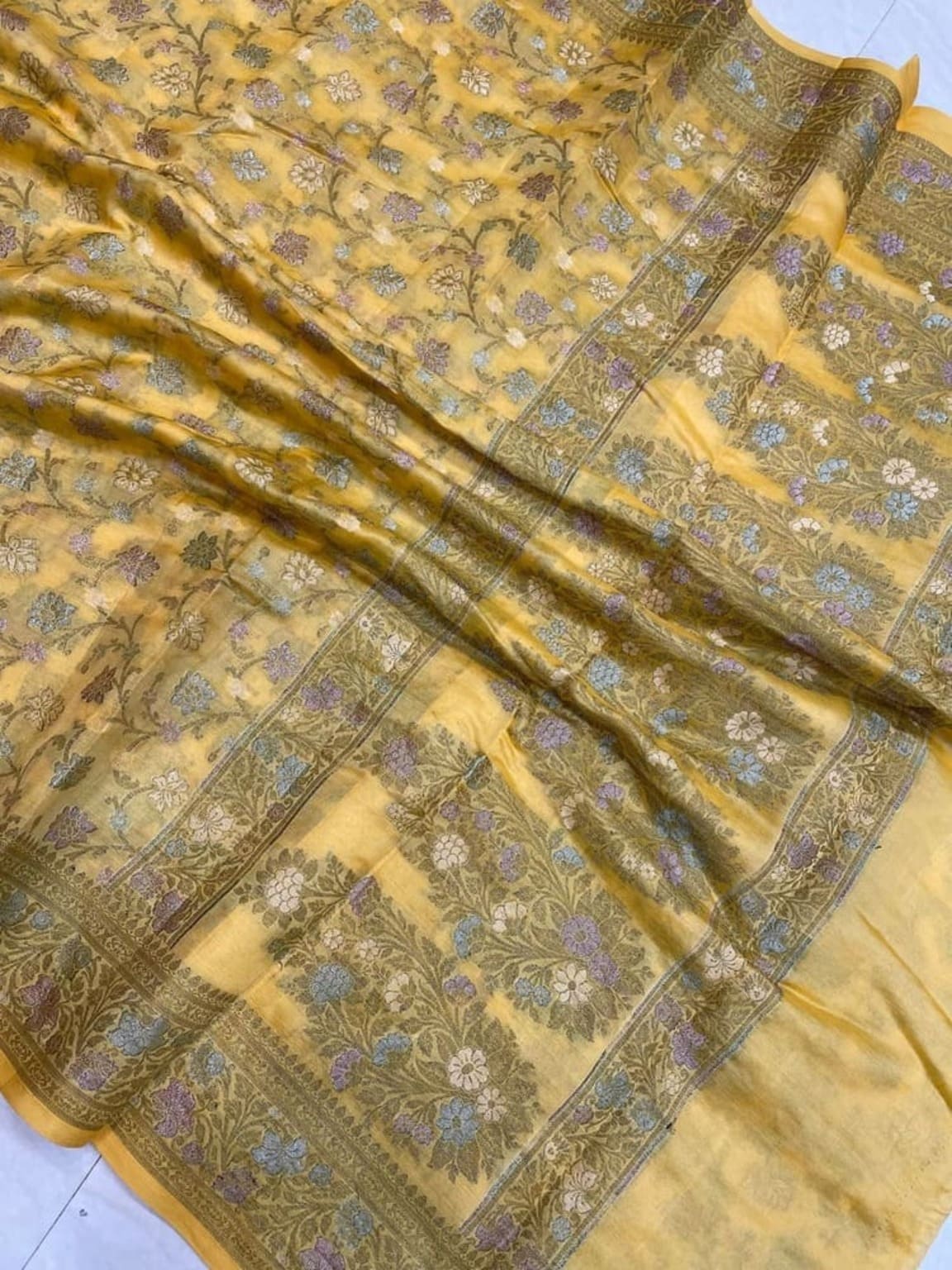Mustard-yellow saree closeup showing jacquard floral motifs and ornate border