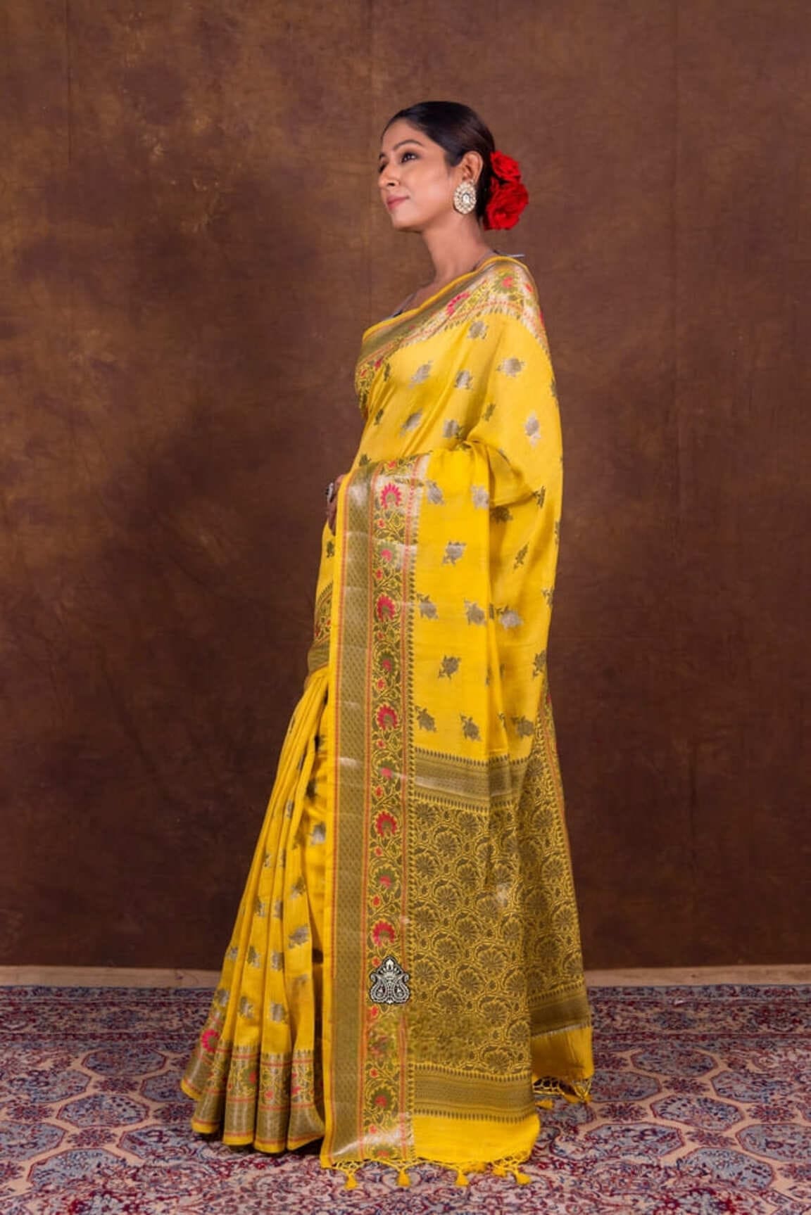 Mustard yellow Banarasi saree with zari-style red-gold border and decorative medallions