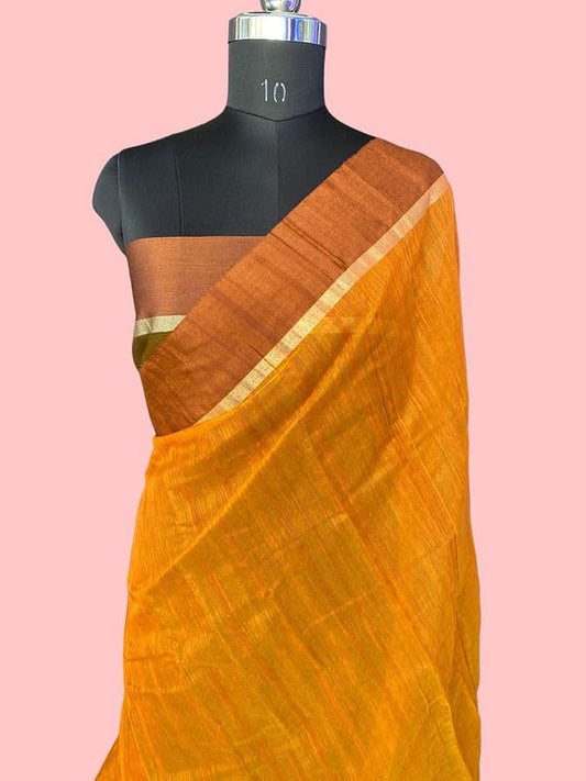Mustard silk saree draped on mannequin, white-striped pallu border