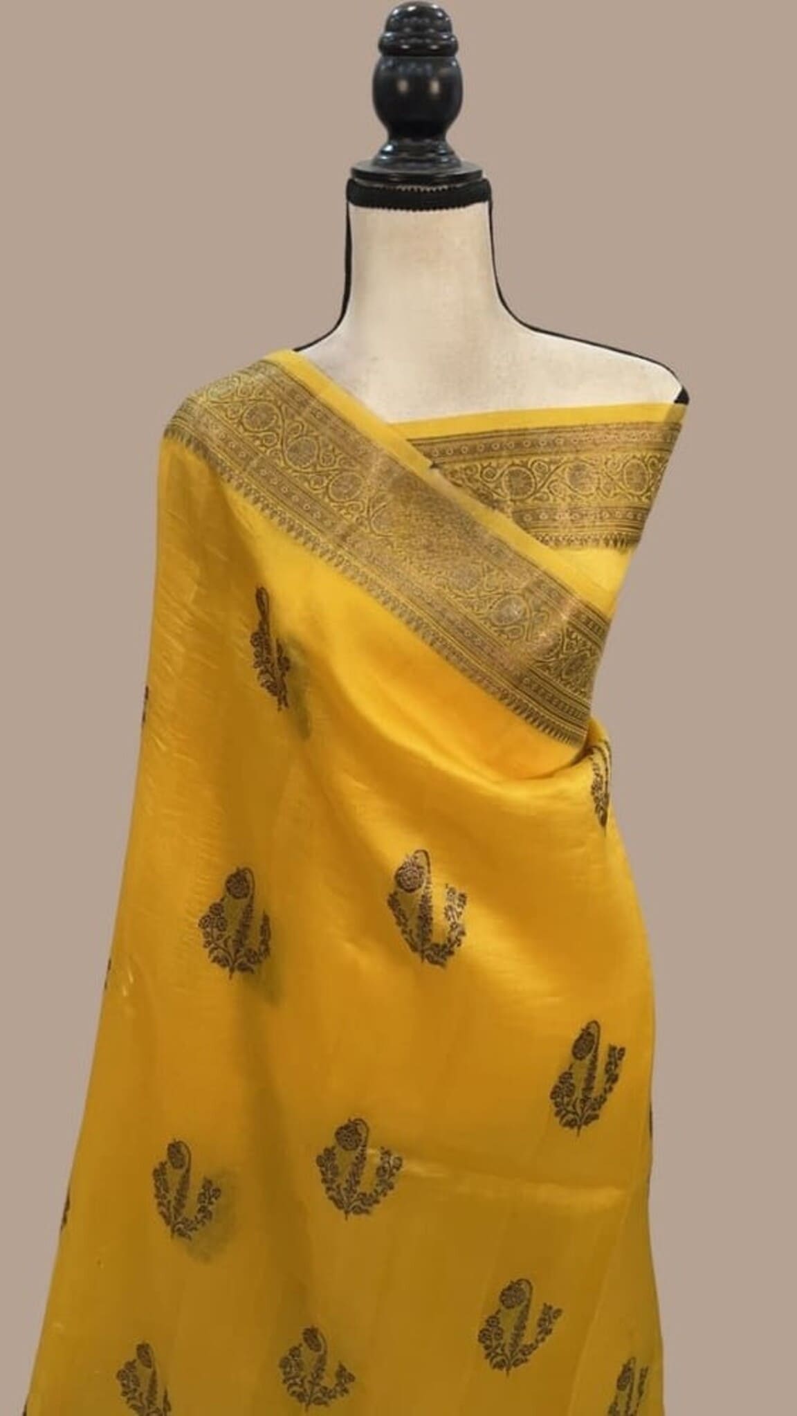 Mustard yellow draped Banarasi saree with gold border and scattered leaf motifs