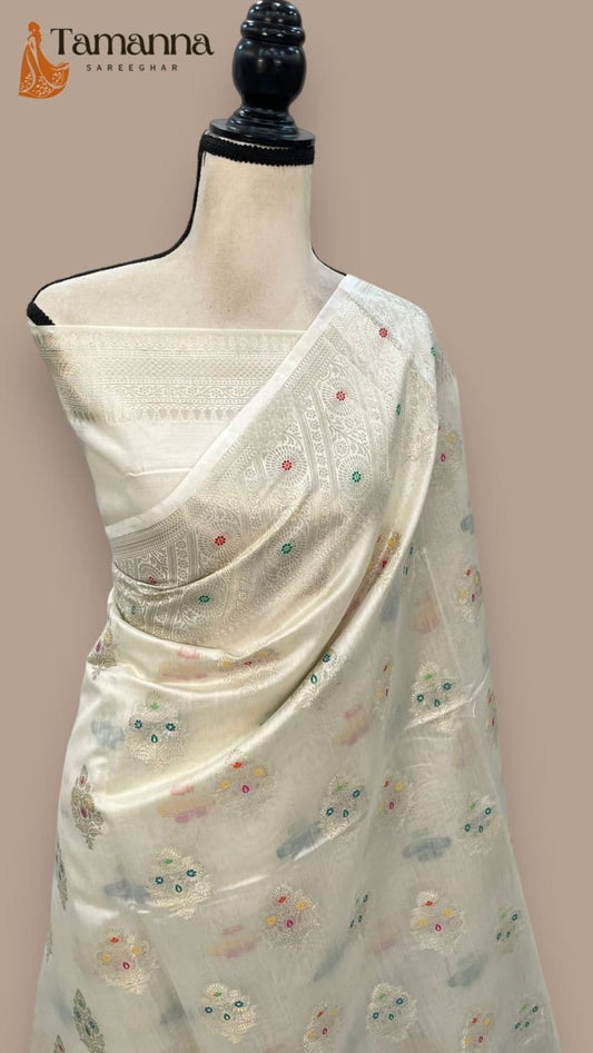 Off-white silk saree draped with diagonal pallu border and multicolor motifs