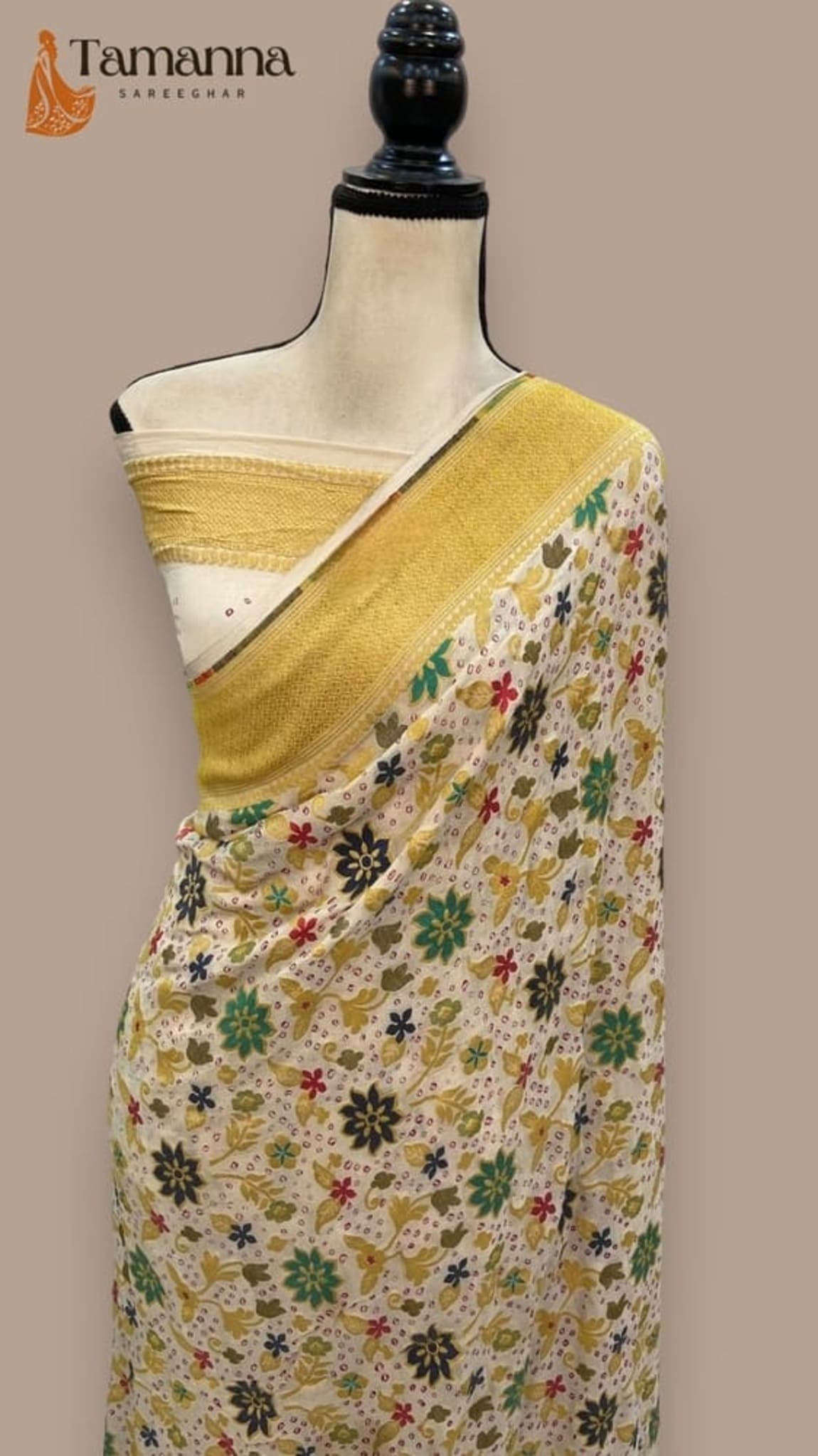 Off-white and yellow saree with multicolor floral motifs, draped on mannequin