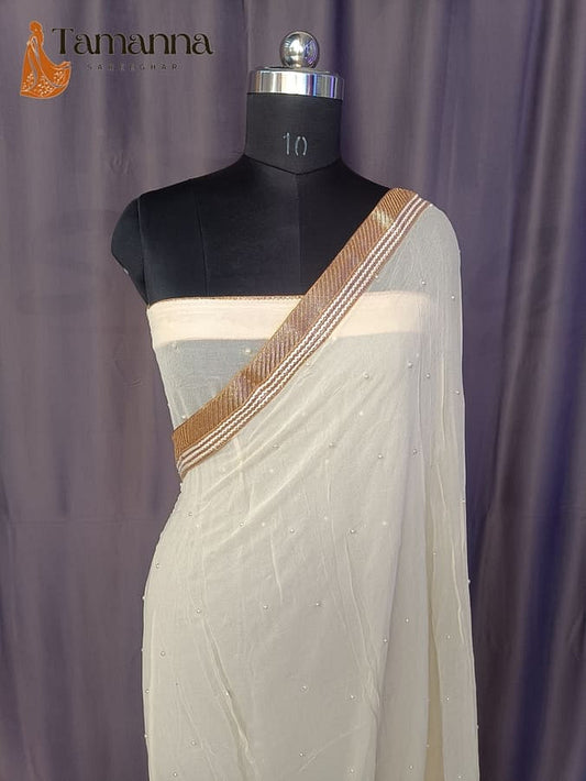 Ivory georgette saree with gold-trim border and scattered pearl embellishments