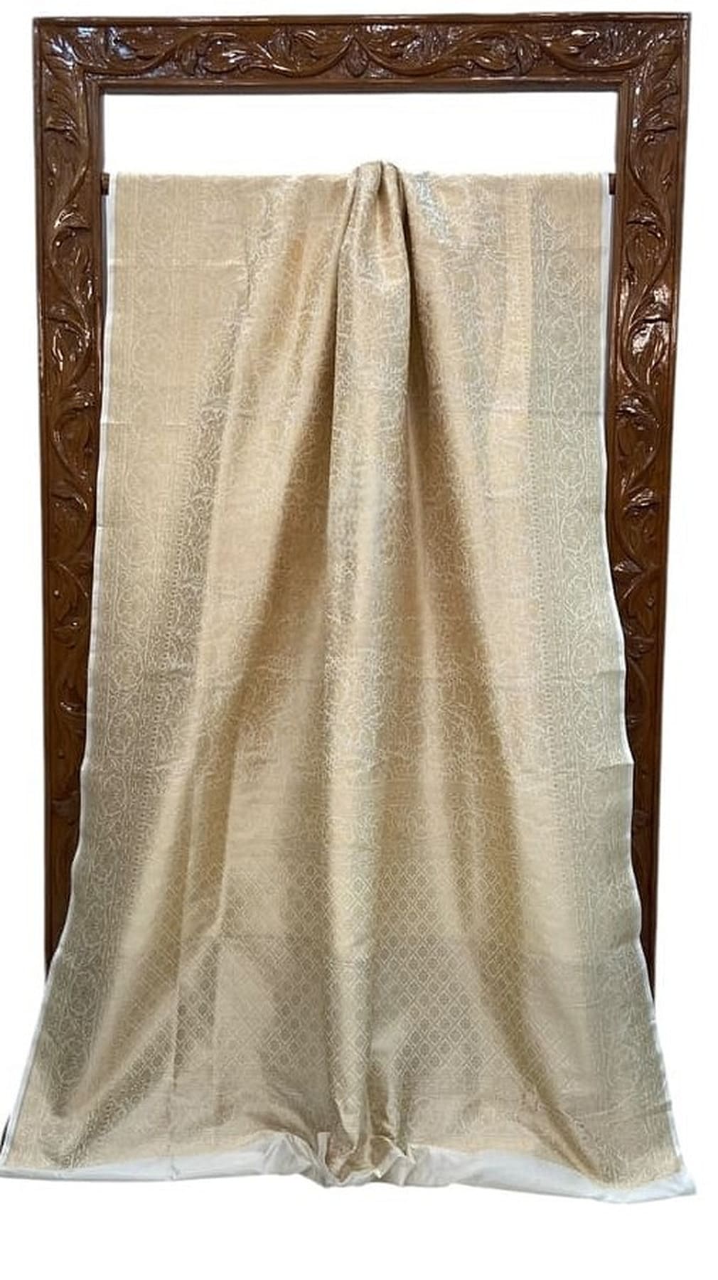 Off-white katan silk saree draped flat, subtle gold brocade pattern