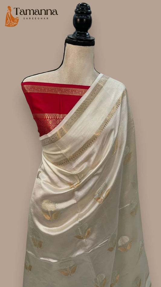 Off-white saree on mannequin with red pallu border and gold leaf zari detailing