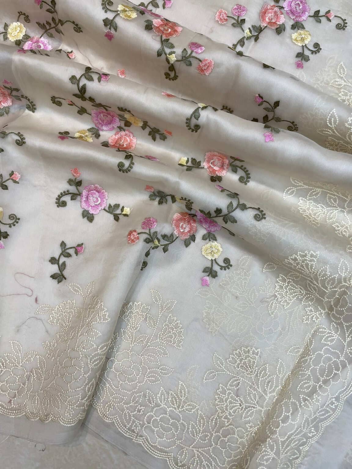 Off-white organza saree end with decorative floral vines and woven lace border