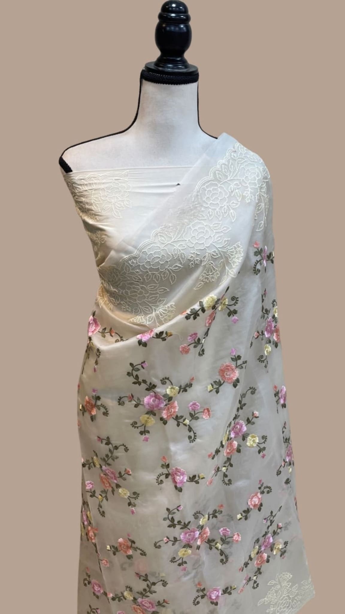 Off-white saree on mannequin with floral print body and lace-like chikankari work