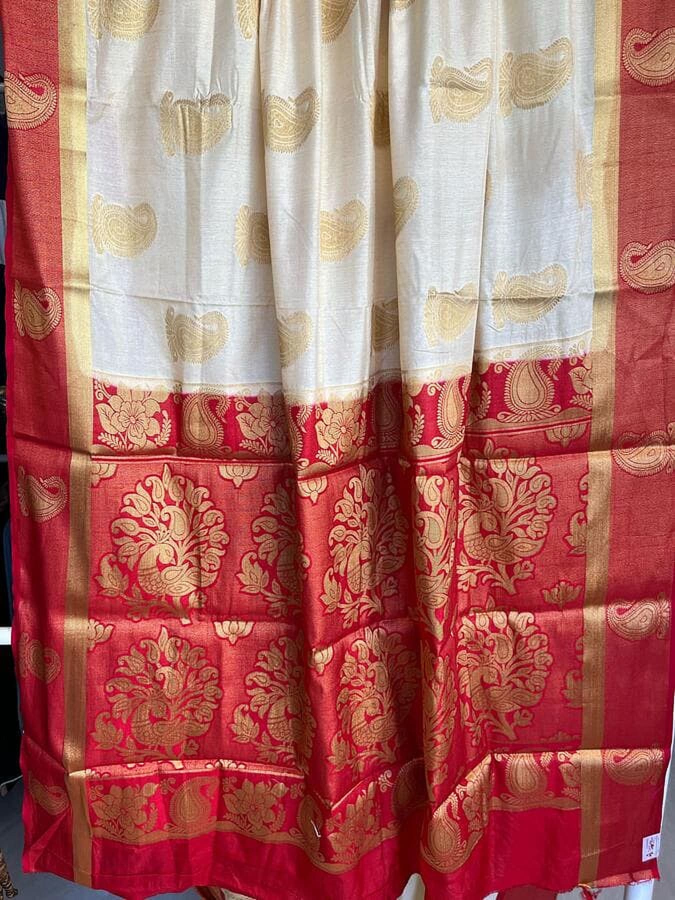 Off-white silk saree with golden motifs and red patterned border, close-up pleats