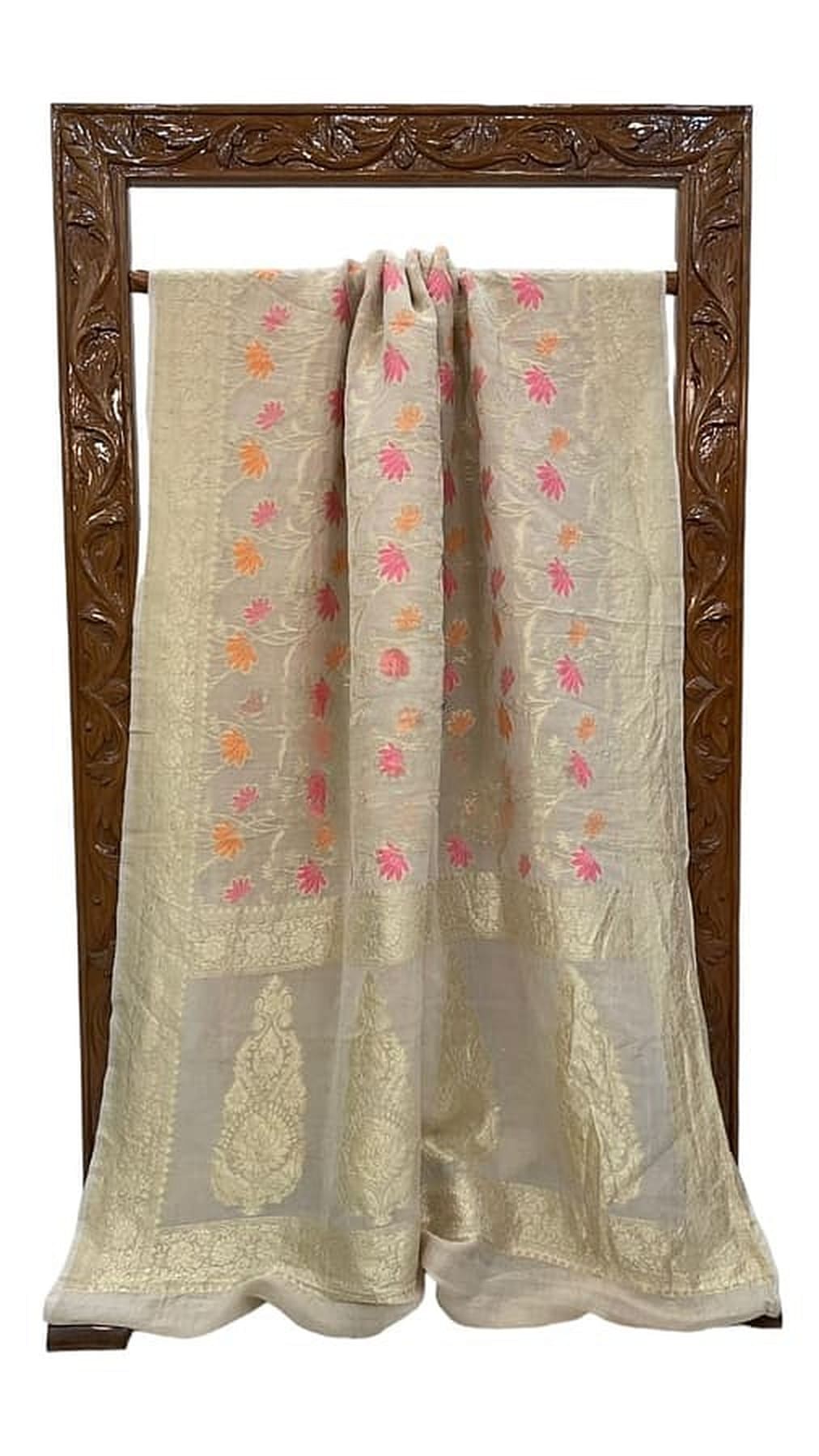 Off-white saree draped with pink and orange floral motifs and patterned border