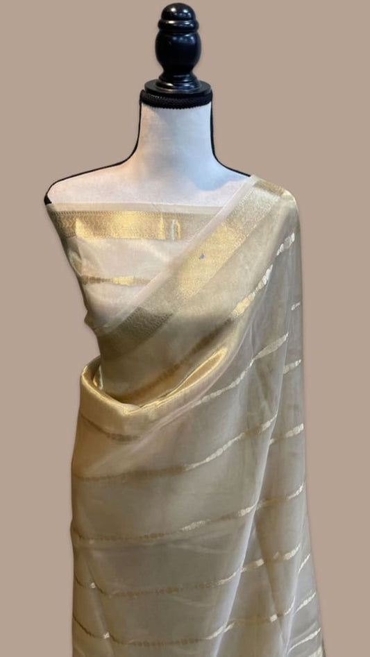 Off-white Banarasi tissue saree with gold zari border, draped on mannequin.