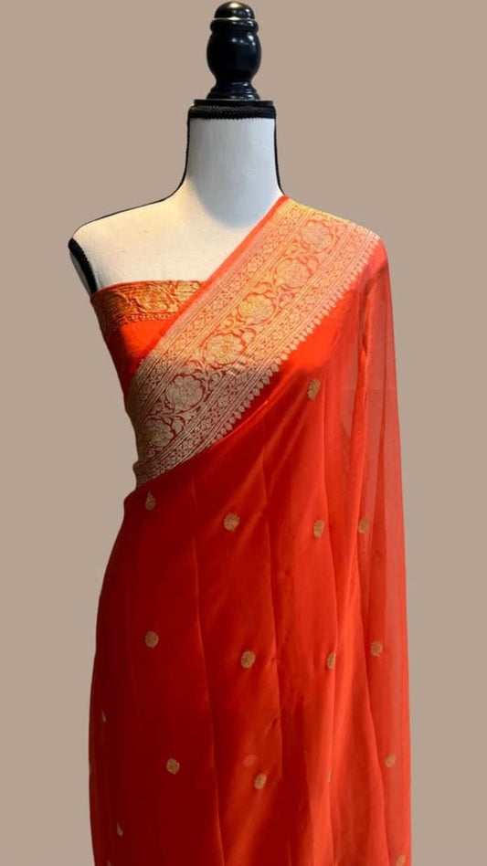 Orange georgette saree on mannequin with gold zari pallu and small scattered motifs