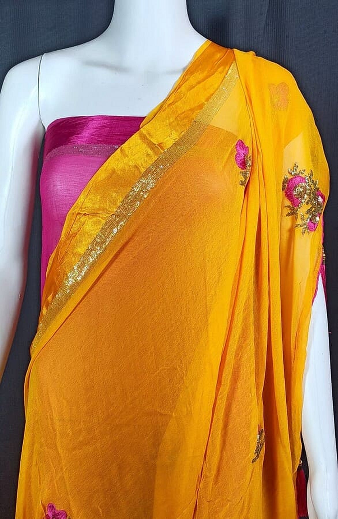 Draped orange saree with gold zari trim and purple floral embroidery on pallu