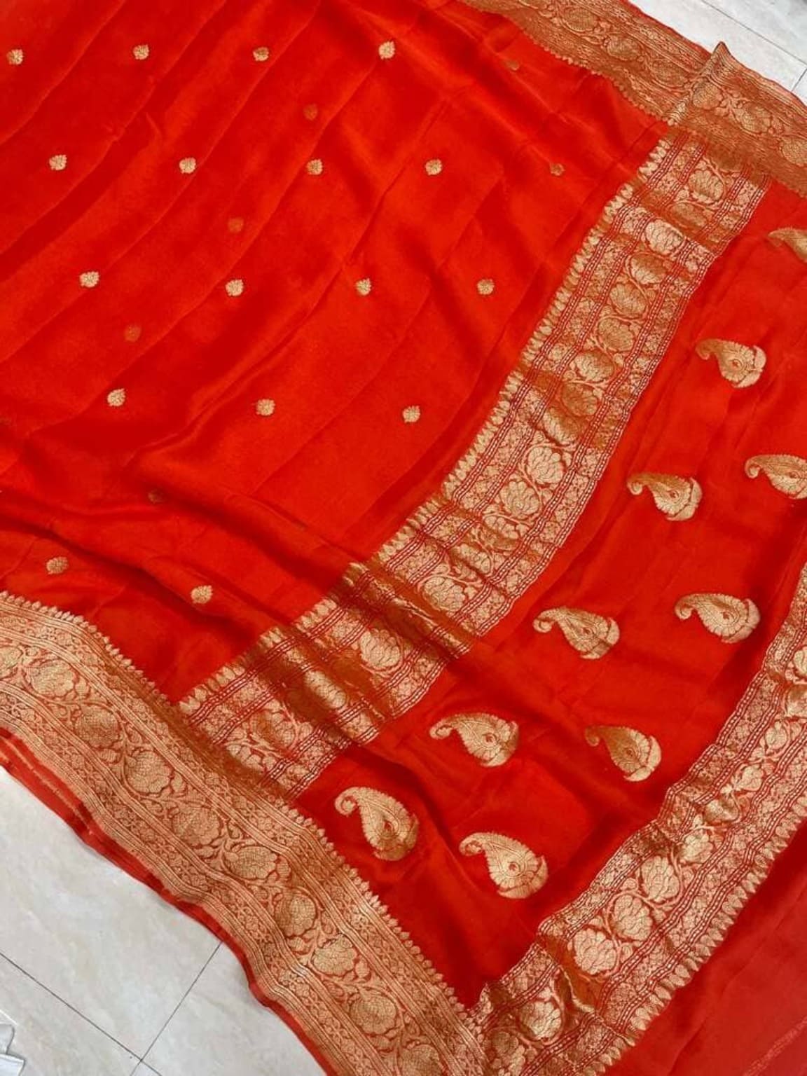 Orange saree close-up with gold zari border and paisley-like motifs