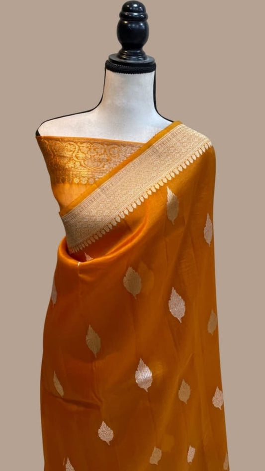 Orange handloom Banarasi saree with golden leaf motifs and wide silver-gold border