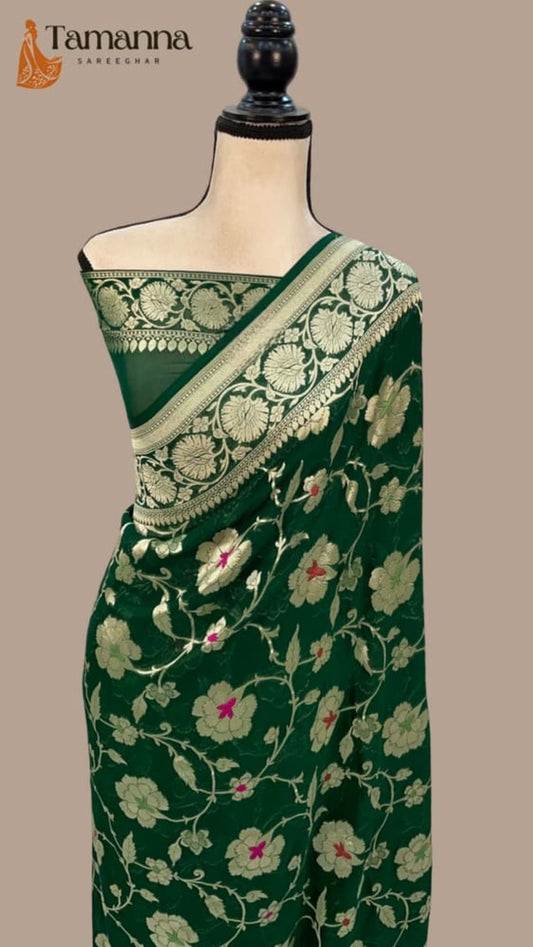 Dark green saree draped on mannequin with ornate light green-gold border and floral motifs