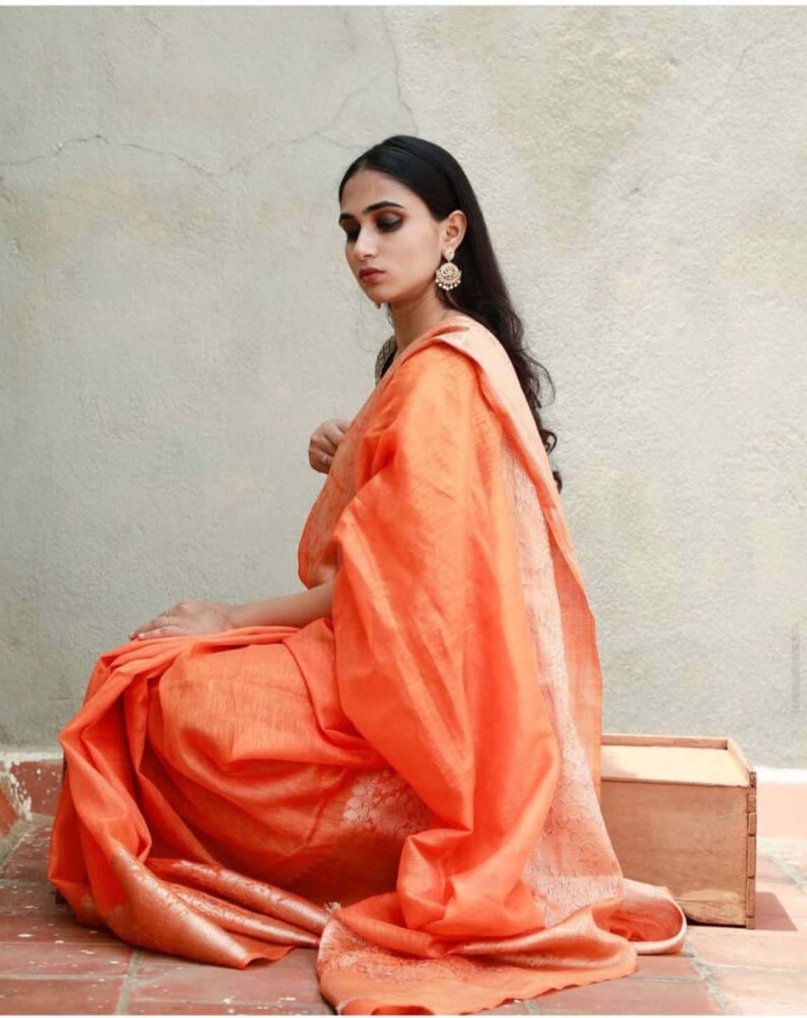 Peach-orange linen saree with draped pallu, cream highlights, and zari border