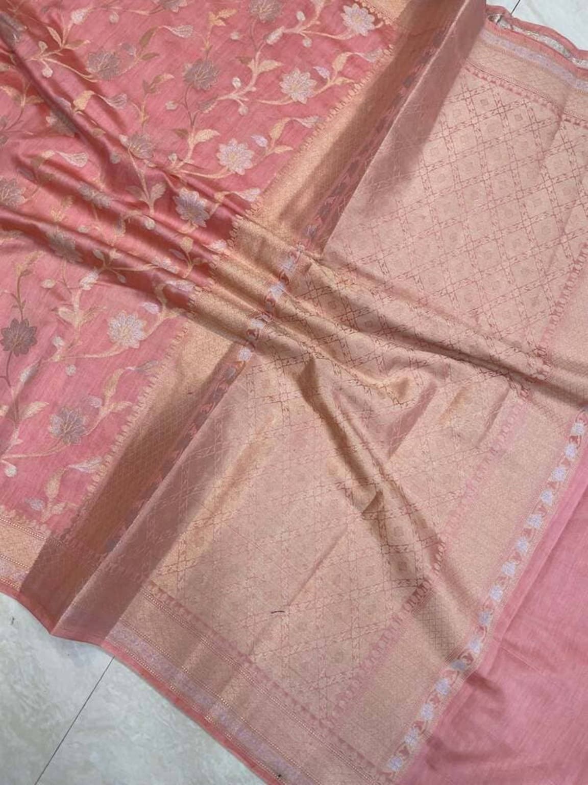 Pink saree fabric with gold woven strip and repeating floral vine designs near border