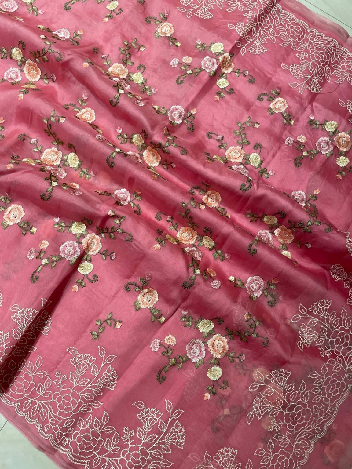 Pink organza saree close-up with scattered rose buds and white vine zari work