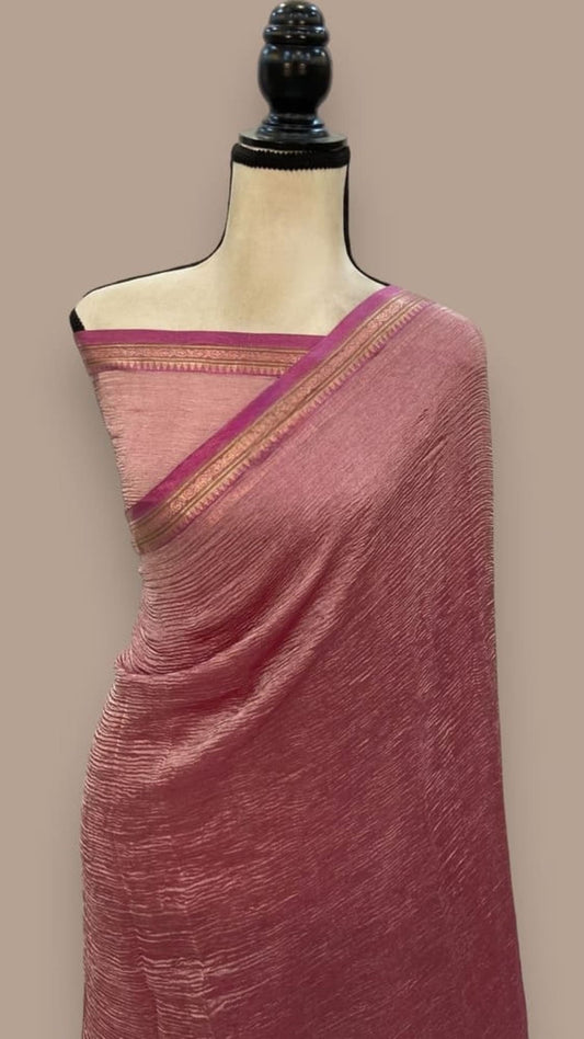 Pink saree draped on mannequin, with magenta and gold woven border at pallu