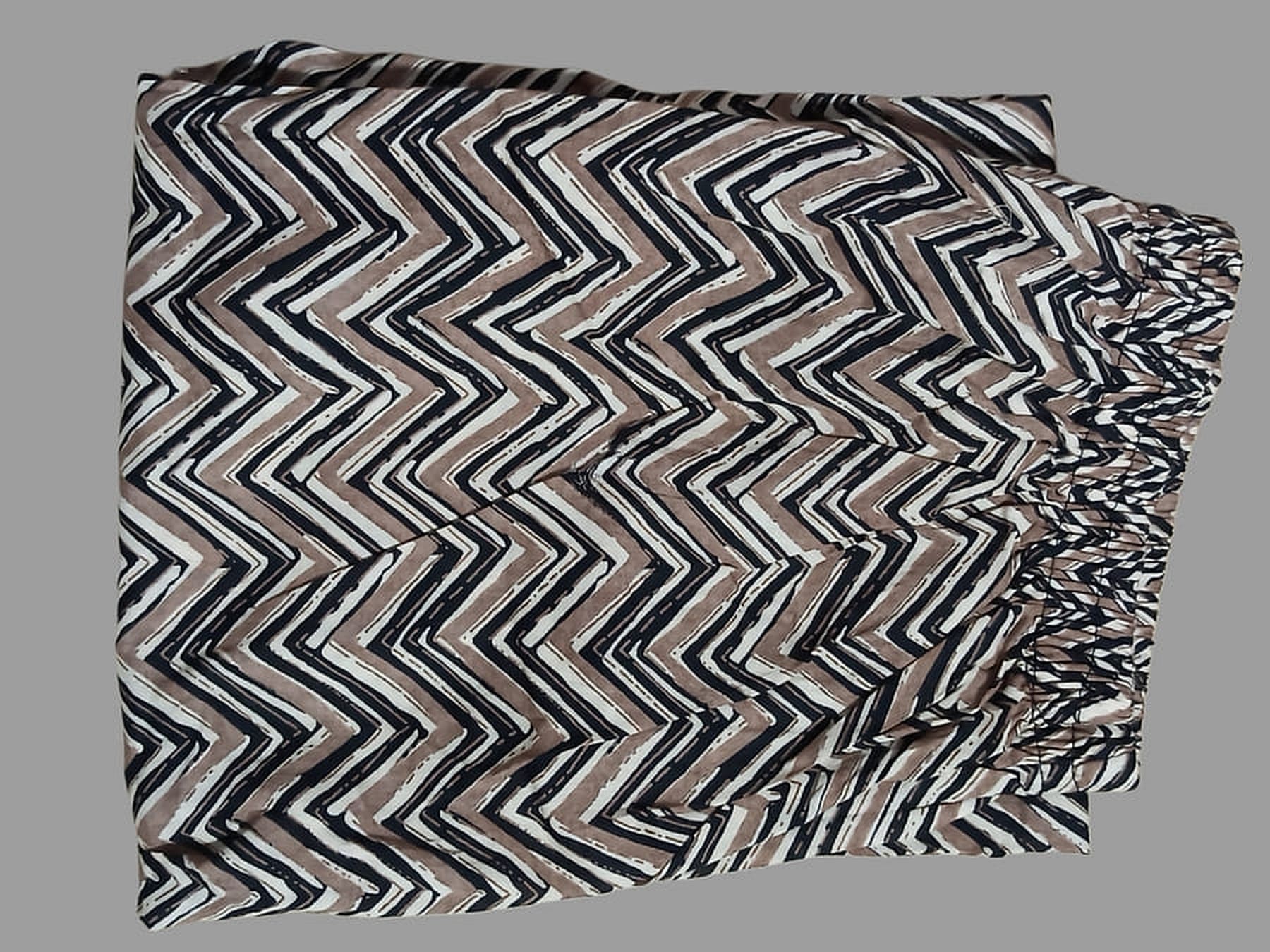 Chevron printed cotton fabric swatch in black and white with beige accents, folded