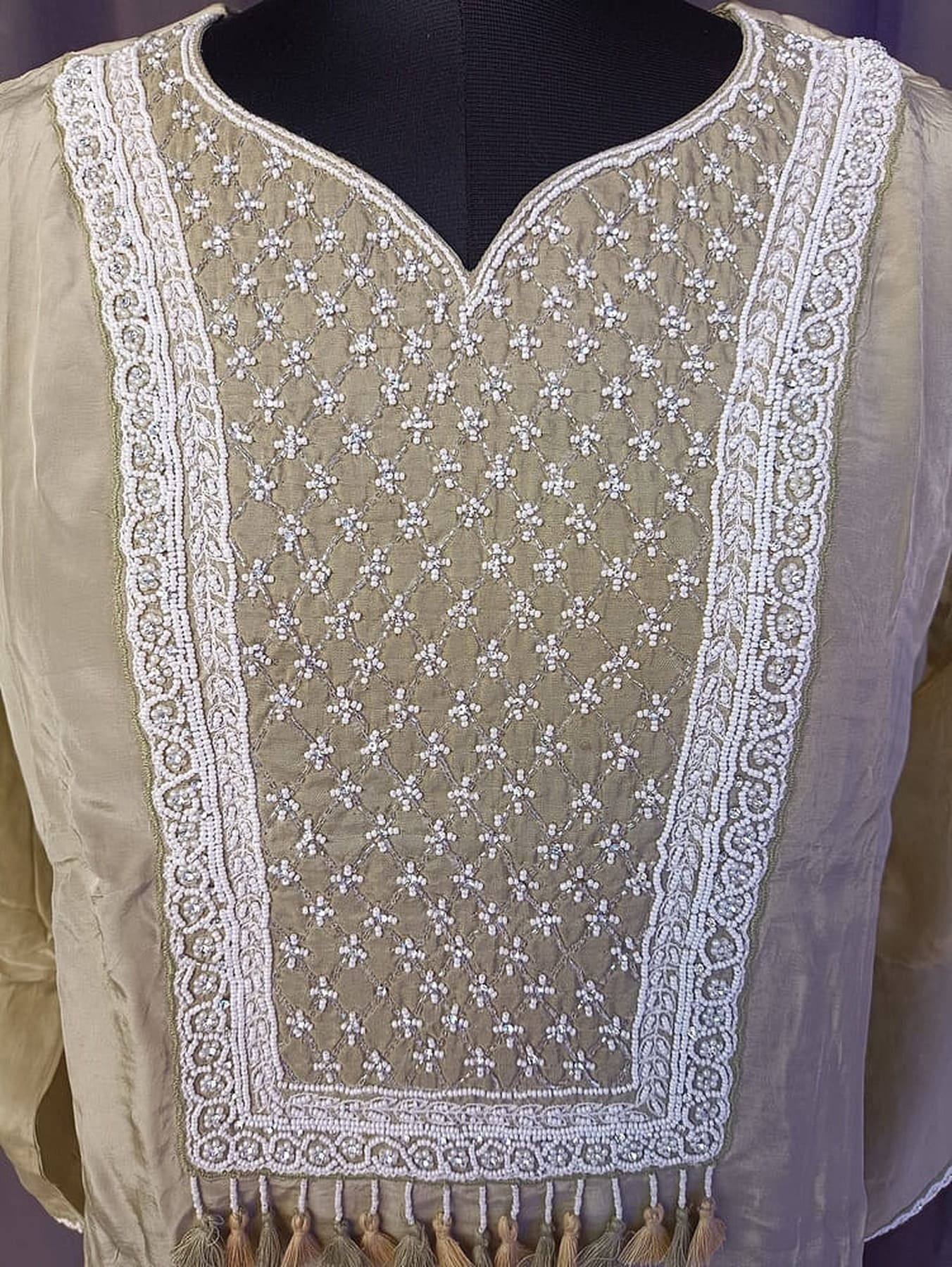 Beige kurta front closeup with lattice embroidery, scalloped border trim and tassels