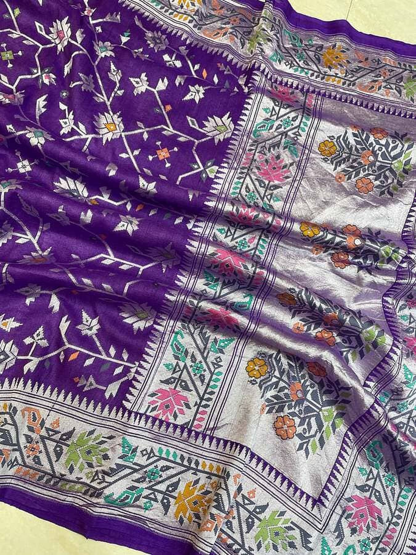 Purple Banarasi saree fabric close-up with multicolor border stripes and motifs
