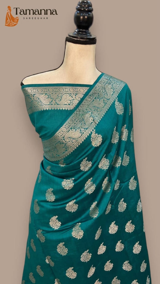 Teal silk saree on mannequin, gold zari pallu border with scattered floral motifs