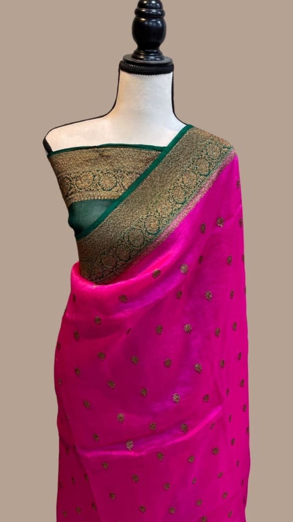 Bright pink Banarasi saree with tiny gold motifs and dark green border, draped on mannequin