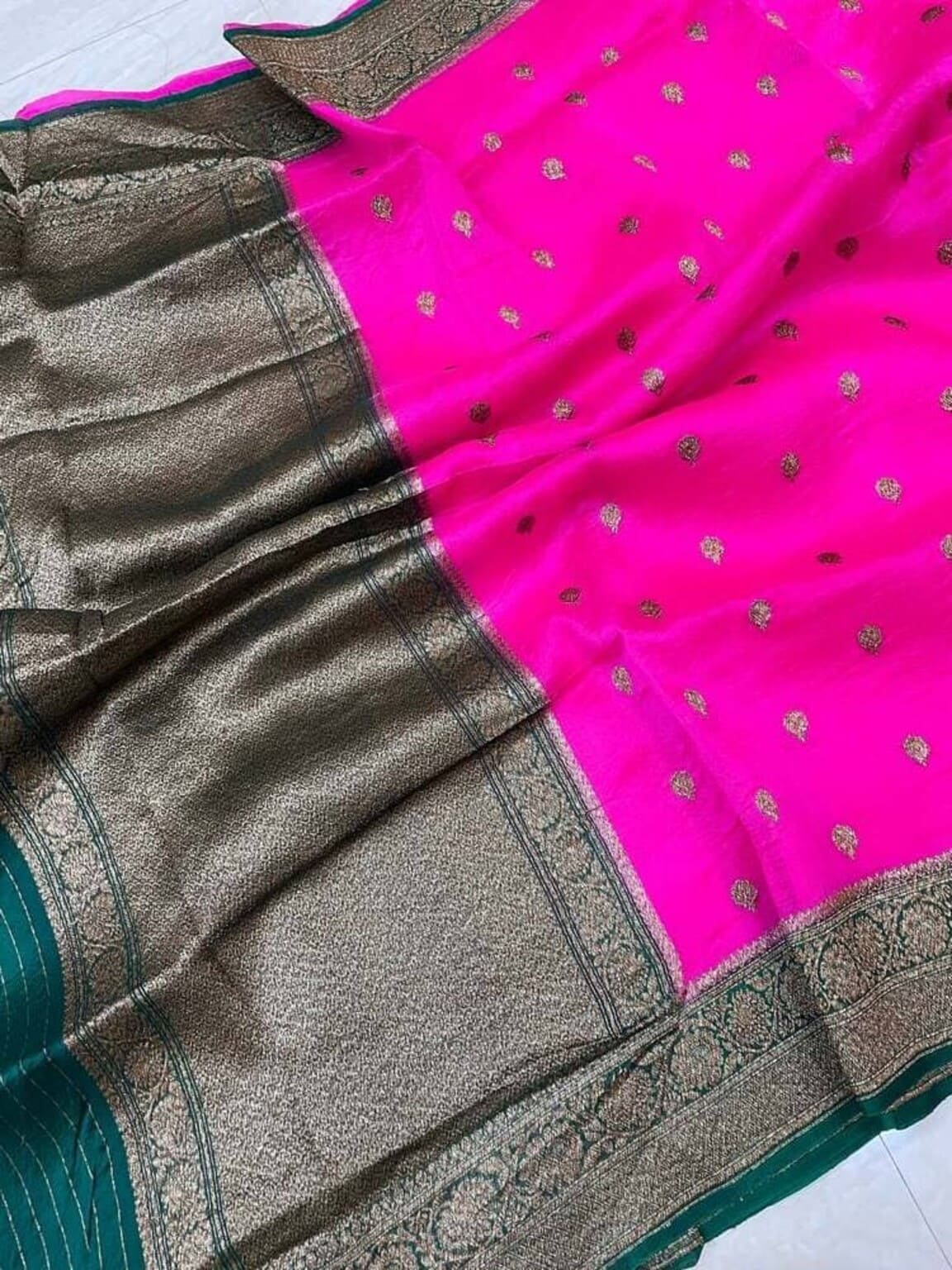 Banarasi saree close-up: bright pink fabric with tiny gold motifs and dark patterned border