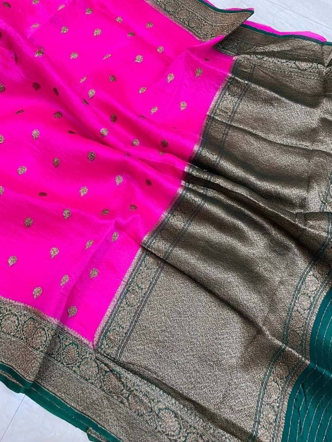 Banarasi saree close-up of grey pallu with teal-green border beside bright pink tiny motifs