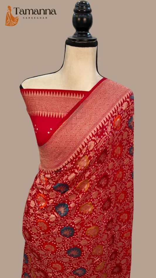 Red saree draped on mannequin with patterned pallu border and scattered floral motifs