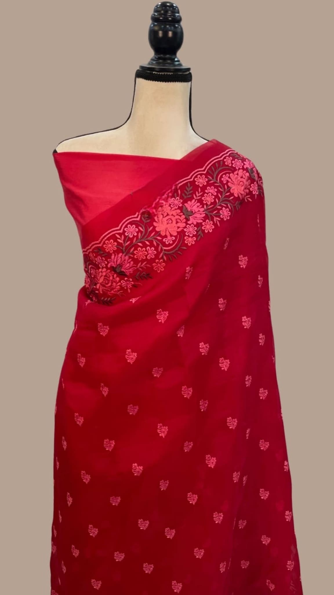 Red organza saree on mannequin with pink floral border and dotted buti accents