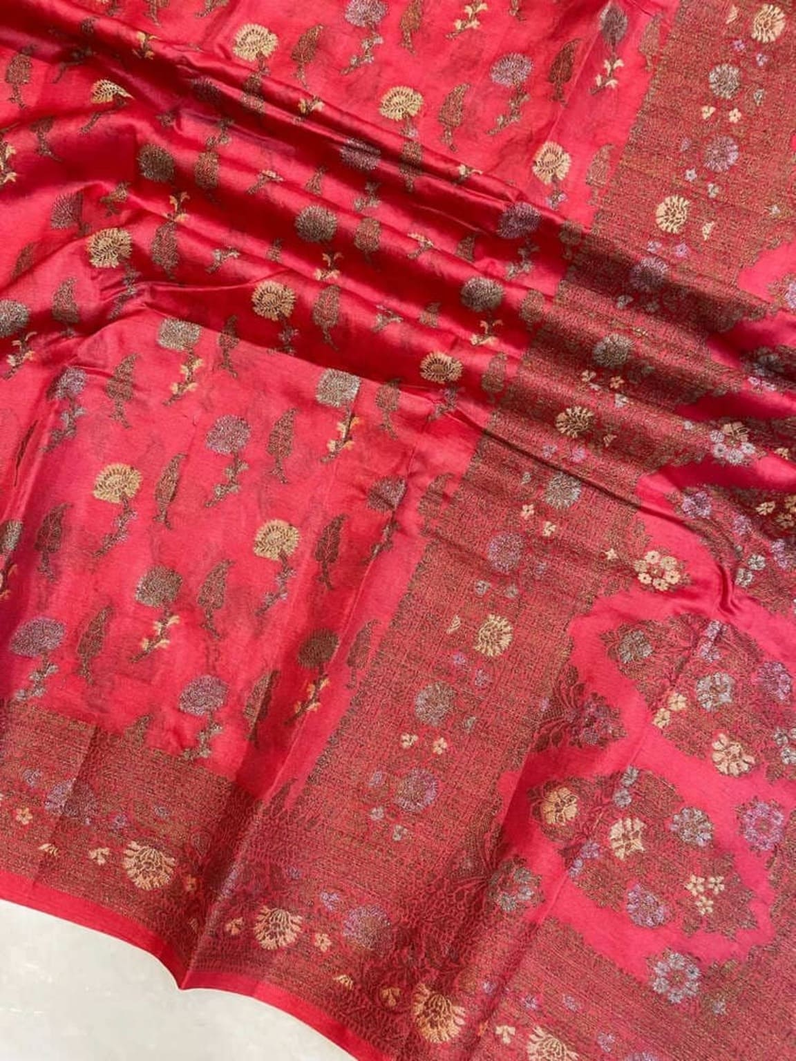 Red saree close-up with gold zari butti sprigs and decorative border on pallu edge