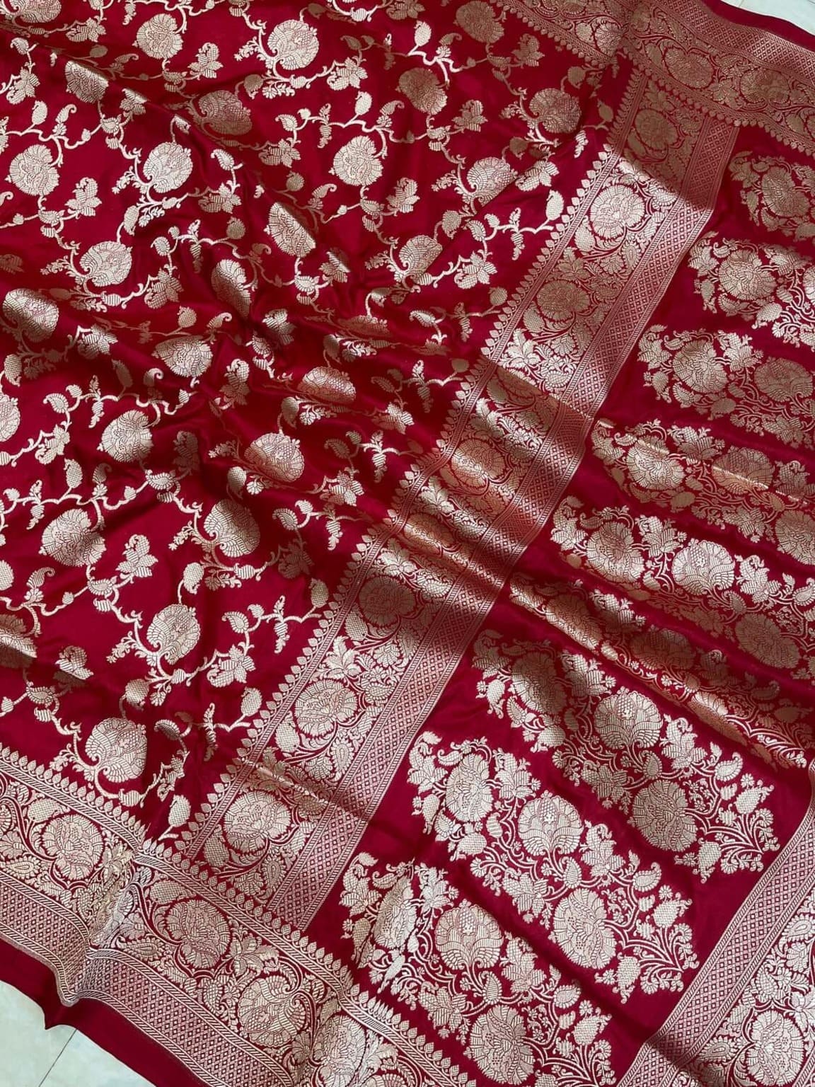 Red silk saree close-up: all-over jaal motifs and gold-toned woven border strip