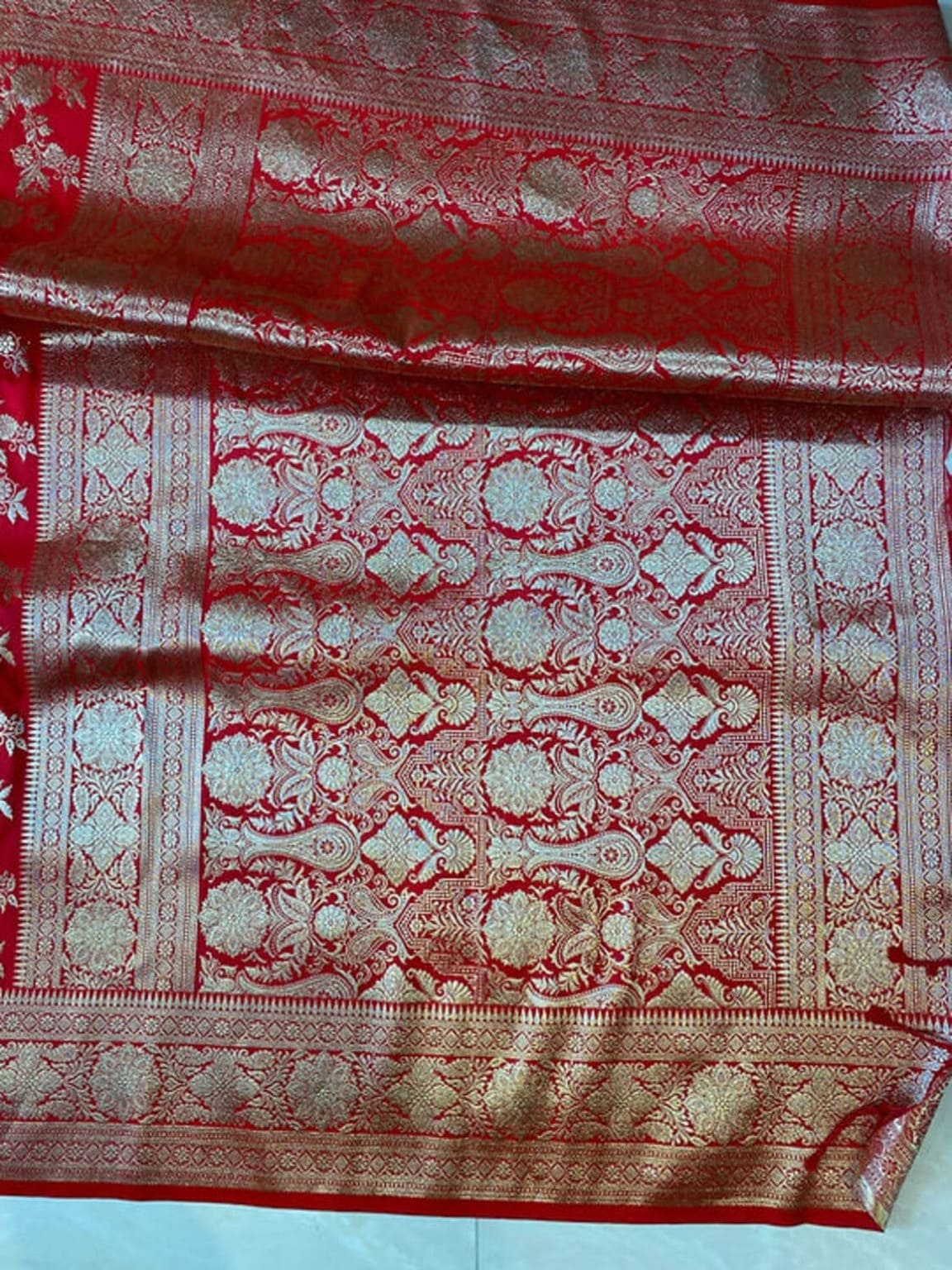 Red saree border close-up with gold zari lattice and floral medallions