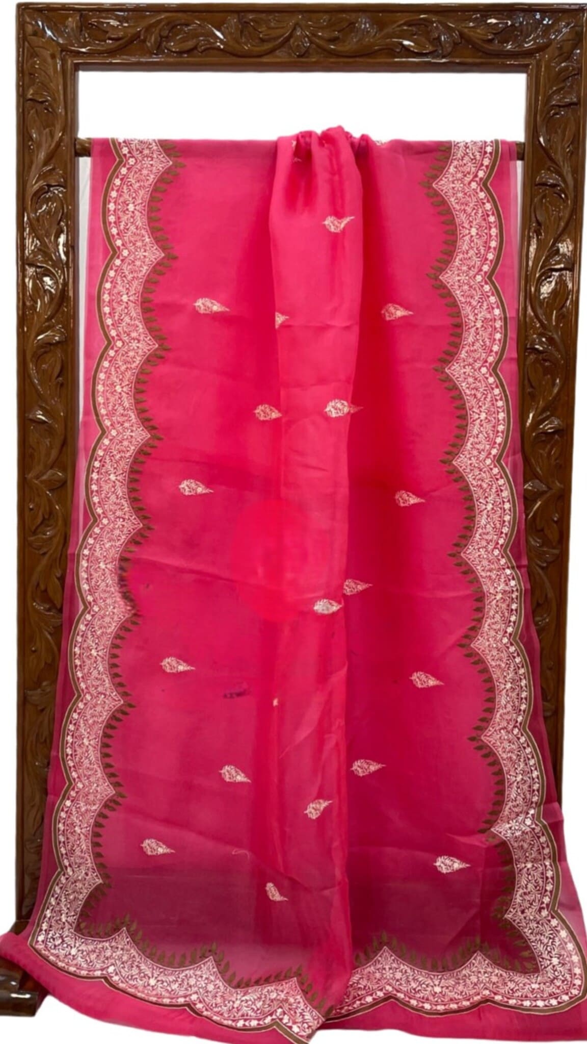 Red organza saree laid flat, scalloped border with paisley embroidery and small motifs