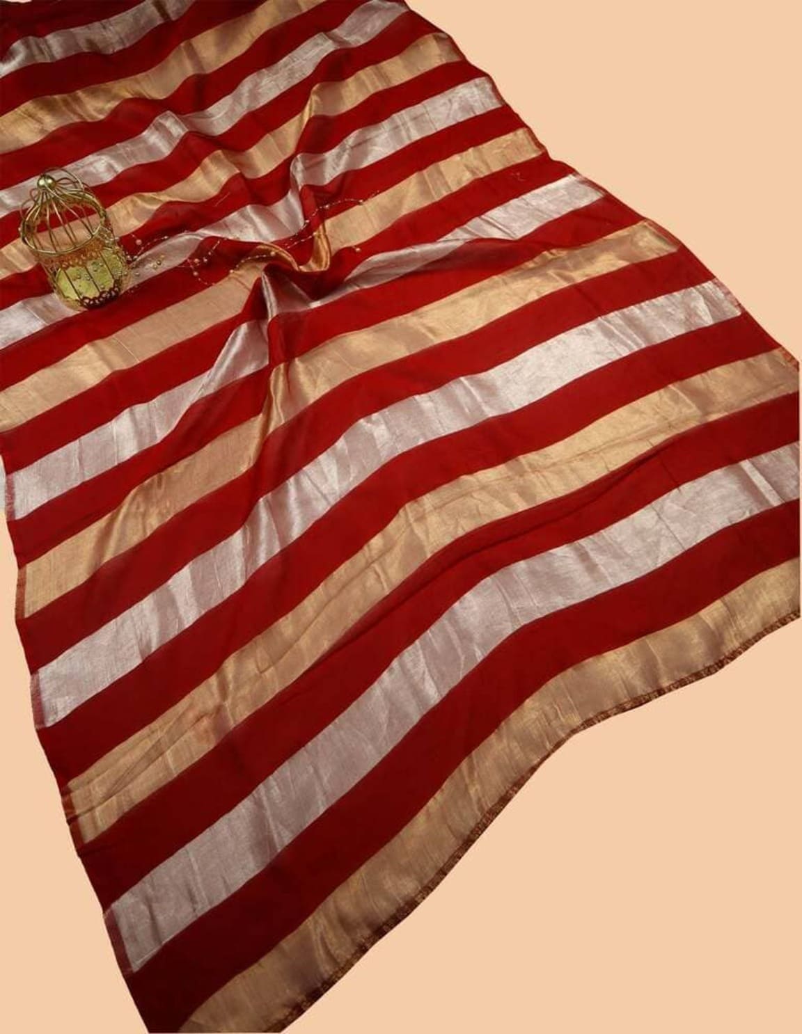Folded red striped tissue saree with gold accents and silver-toned border