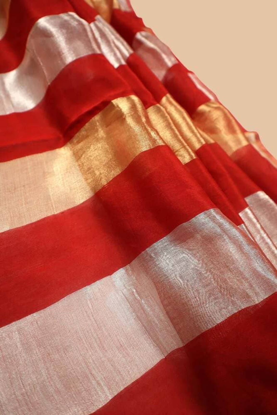 Red tissue saree fabric close-up with alternating stripes and silver sheen