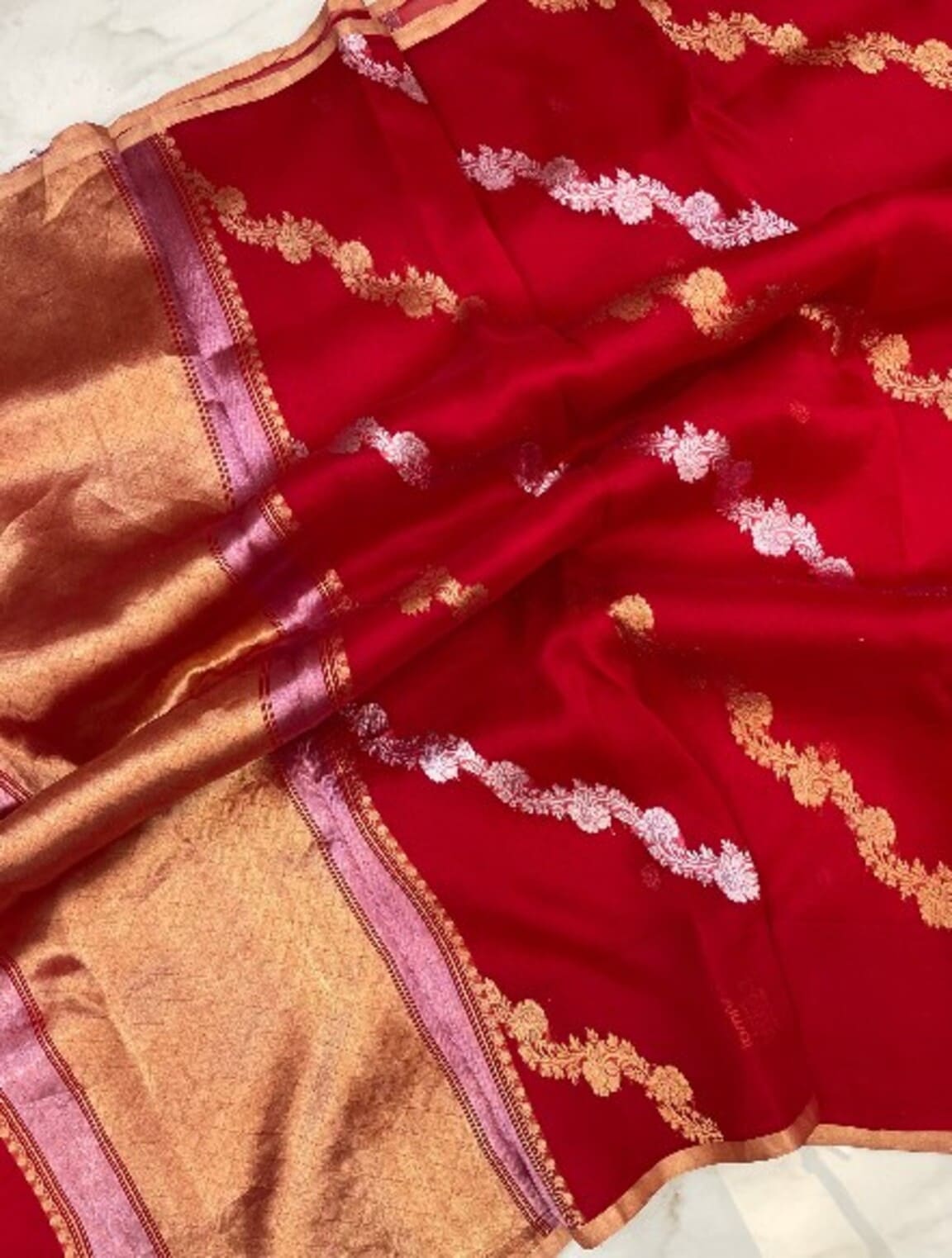 Red saree fabric close-up with gold and silver zari work and wide gold border