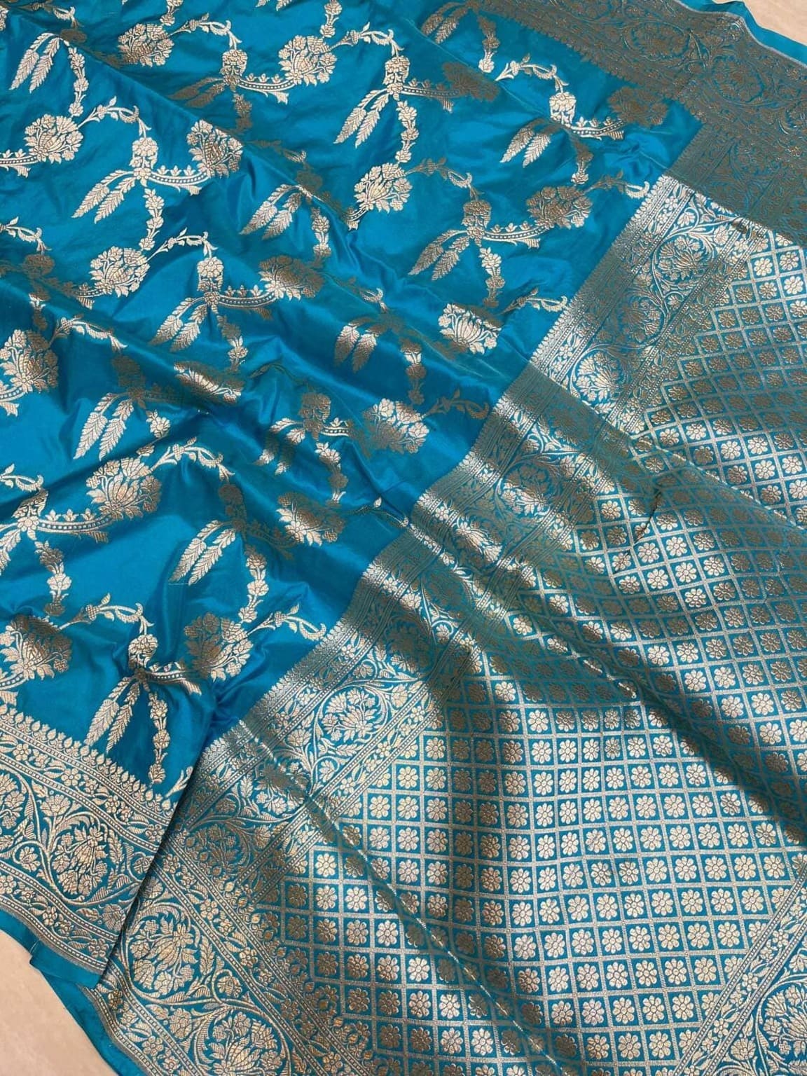 Teal silk saree close-up showing gold motifs and ornate geometric border panel