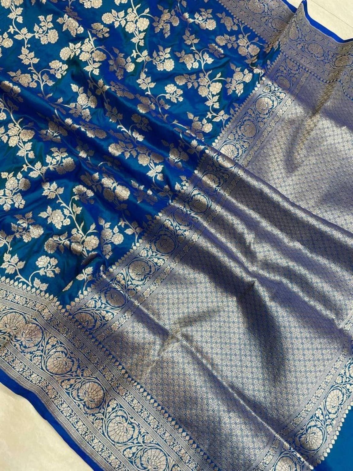 Close-up: royal blue silk saree with silver-toned zari border and floral weave