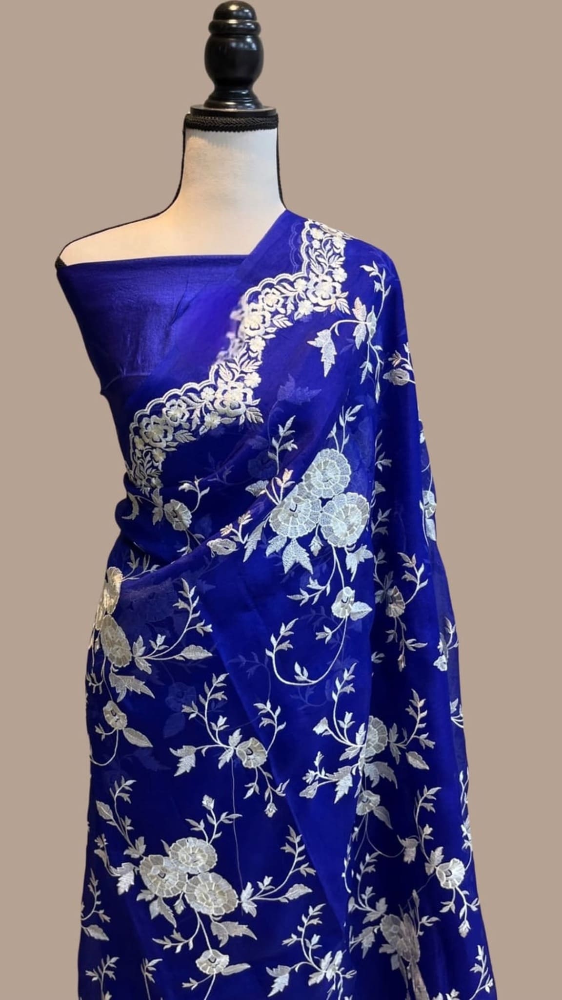 Royal blue organza saree draped on mannequin, white floral chikankari work and border