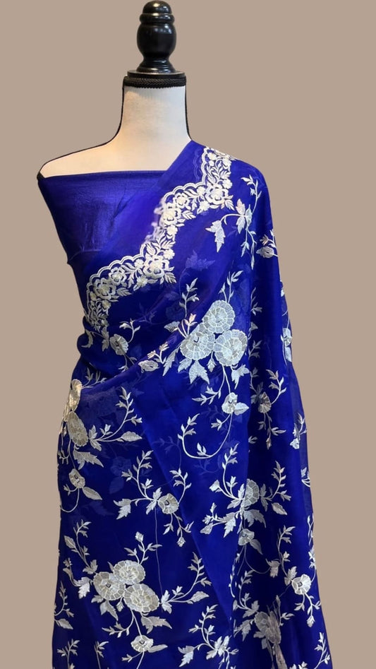 Royal blue organza saree draped on mannequin, white floral chikankari work and border