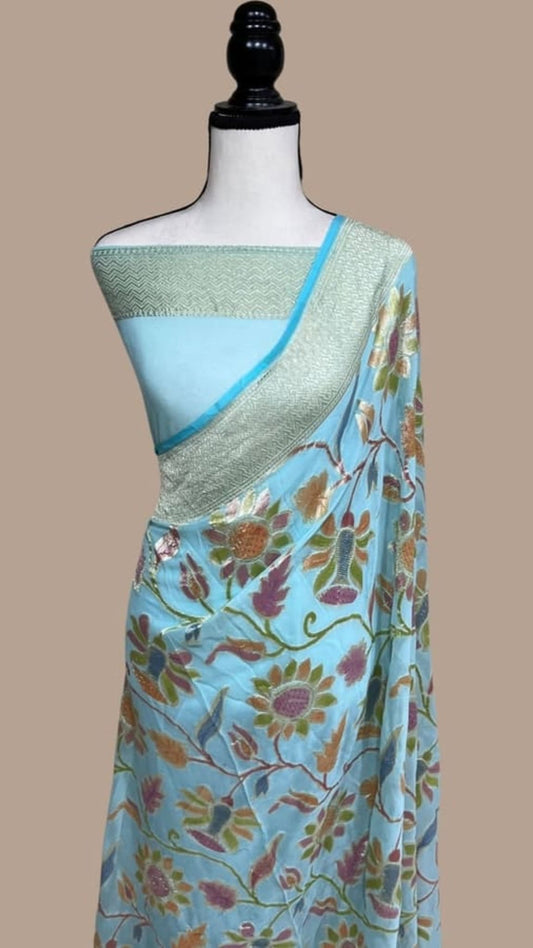 Sea blue floral Banarasi saree draped on mannequin with gold-toned zari border