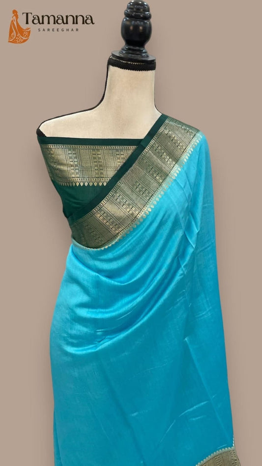 Sky blue silk saree draped on mannequin with dark green woven border along the edge