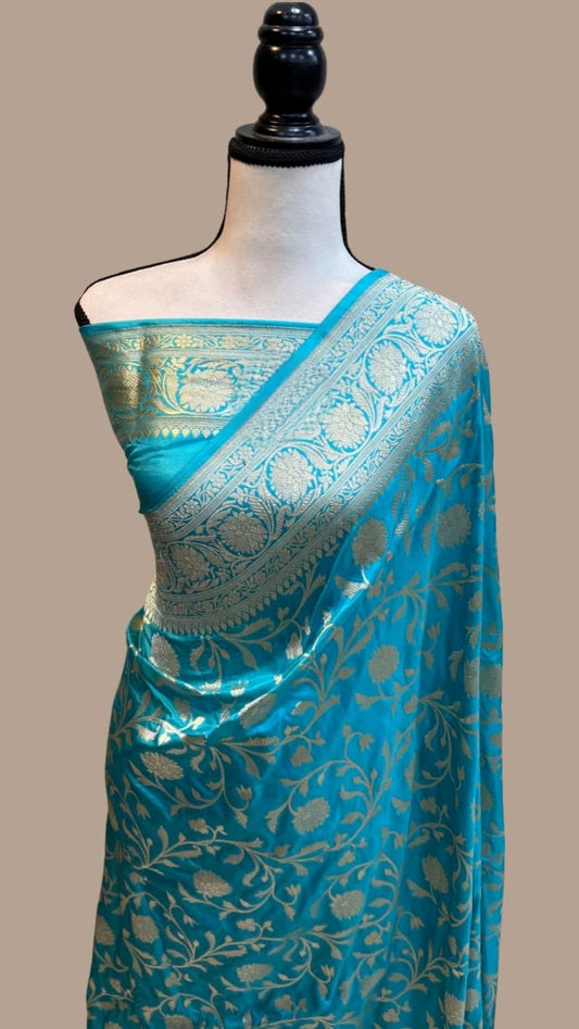 Teal blue silk saree with gold jaal motifs and contrast pallu, draped on mannequin